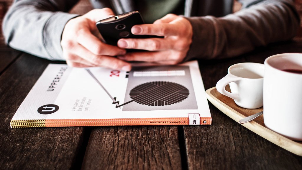 コーヒーの横でスマートフォンを操作する手