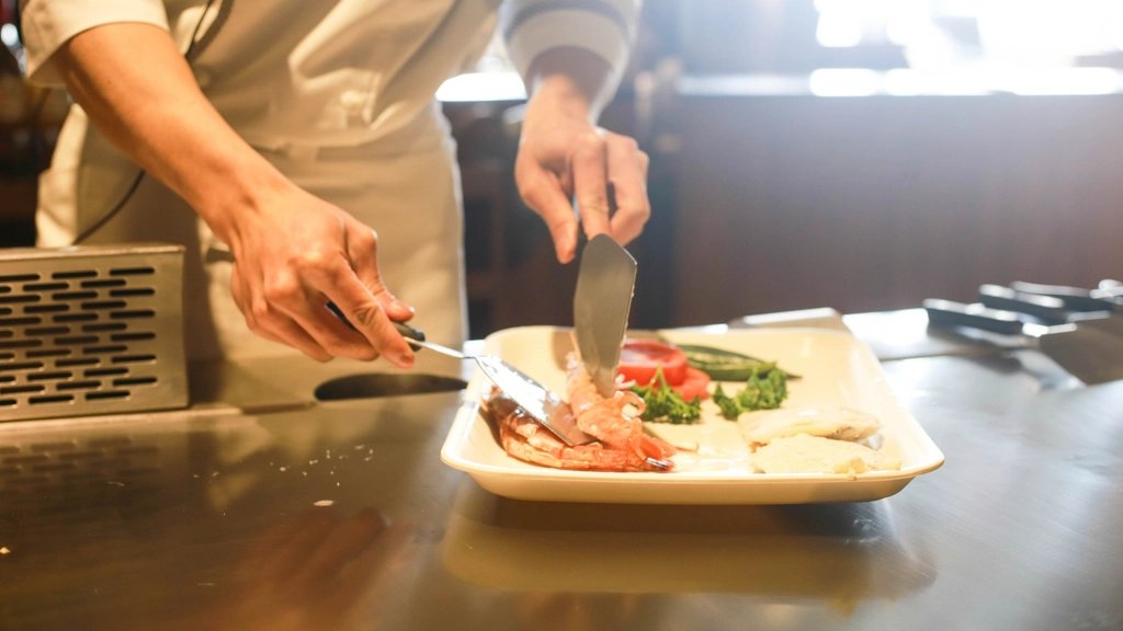 白い皿に料理を仕上げる料理人の手