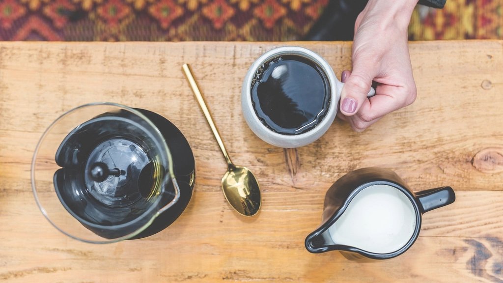 木のテーブルでいれたてのコーヒーを手に取る