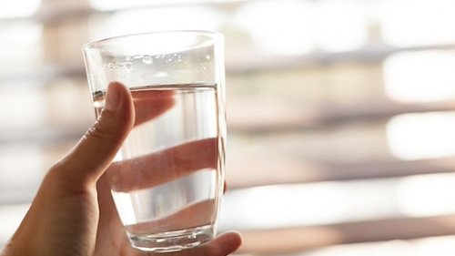 水の入ったグラスを手に持つ